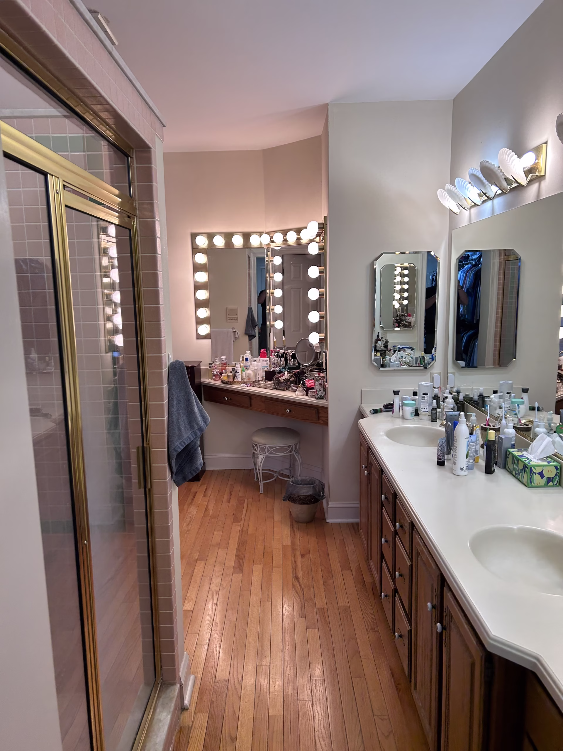 Primary bathroom featuring double vanities, a shower stall, and extensive counters cluttered with personal items in Mechanicsburg, PA
