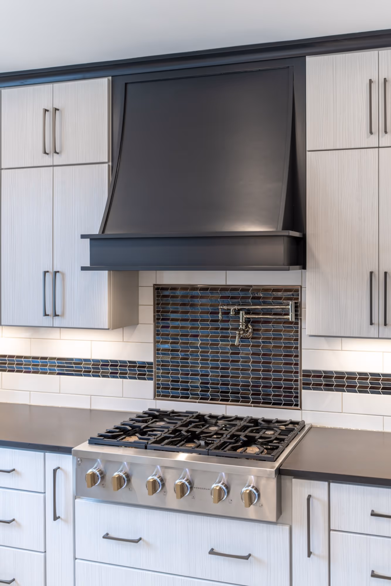 Modern kitchen range with a sleek black hood, adorned with stylish mosaics in Lewisberry, PA.