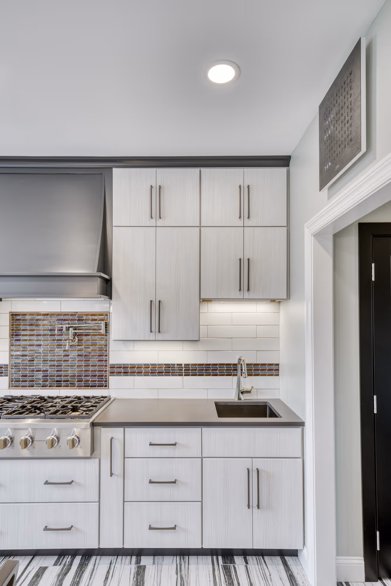 Modern kitchen design in Lewisberry, PA featuring gray wood cabinets, a stainless steel stove, and a stylish mosaic backsplash.
