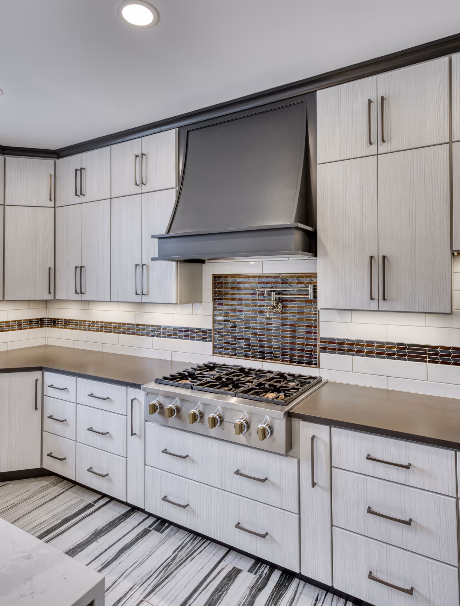 Modern kitchen in Lewisberry, PA with gray countertops, white cabinetry, and stylish tile backsplash.