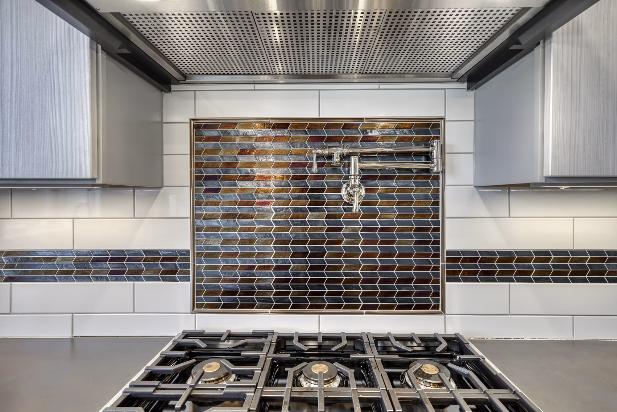 Modern kitchen in Lewisberry, PA featuring a striking copper and gray tile backsplash, stainless steel appliances, and geometric patterns.