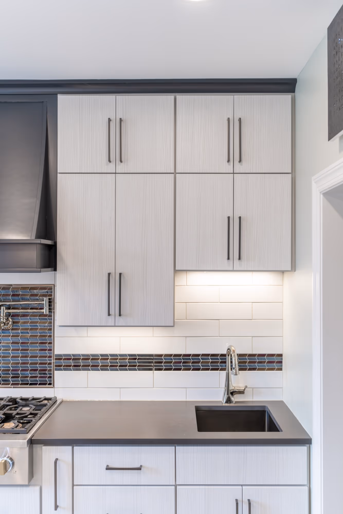 Modern kitchen with sleek gray cabinetry, a small black sink, and colorful mosaic backsplash in lewisberry, pa.