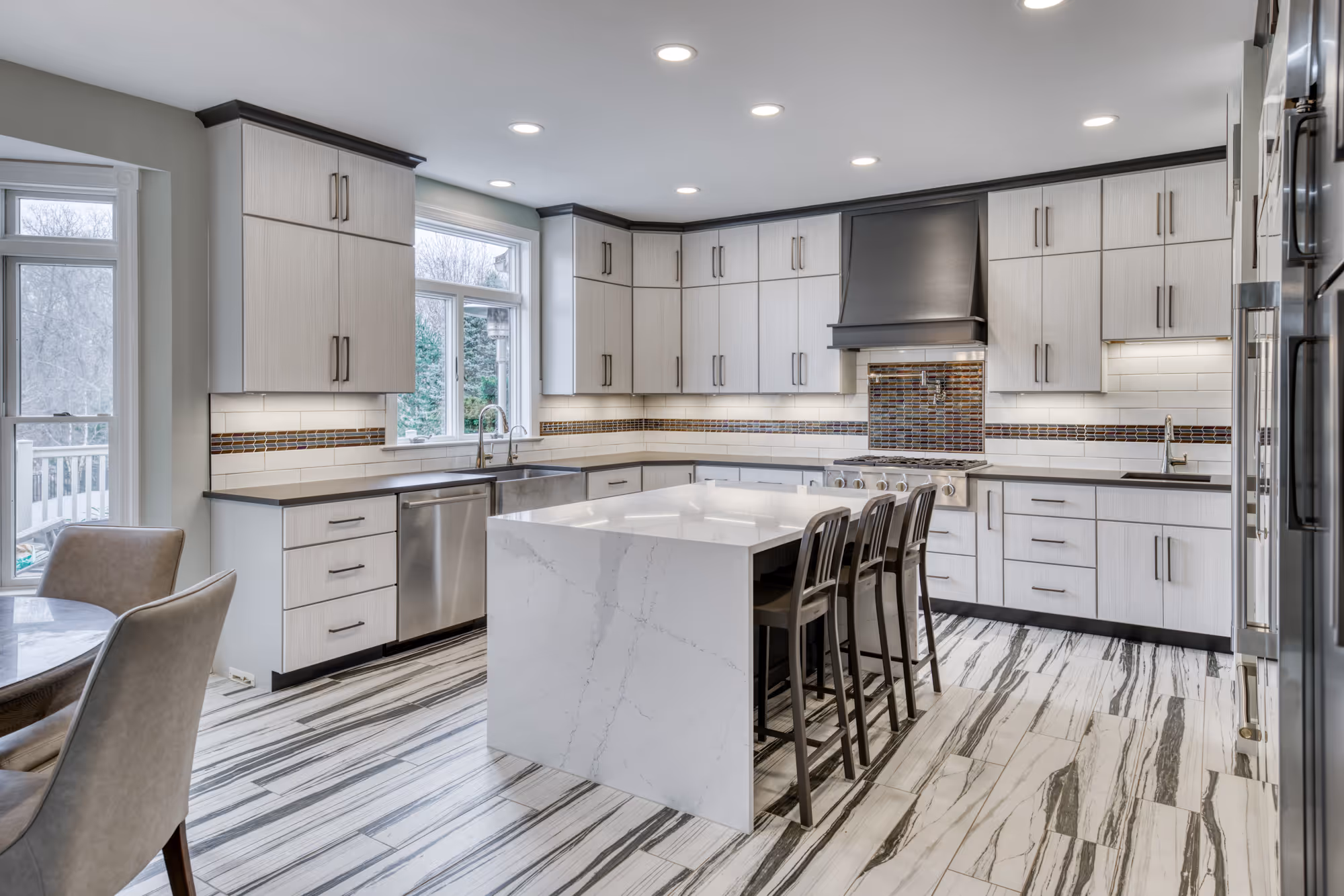 Modern kitchen in Lewisberry, PA with gray and white cabinets, marble island, and unique tiled backsplash.