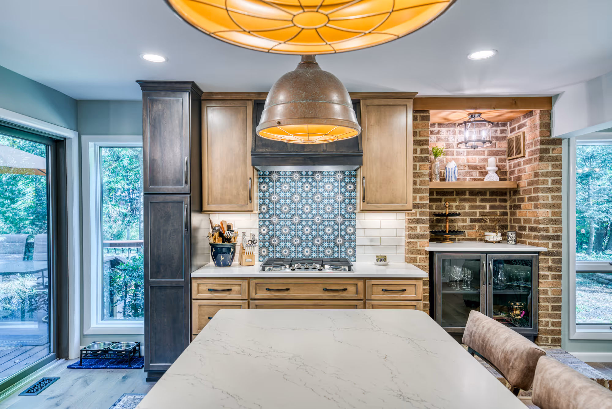 Modern kitchen in Harrisburg, PA featuring a blue tile backsplash, brass fixtures, and wood cabinetry