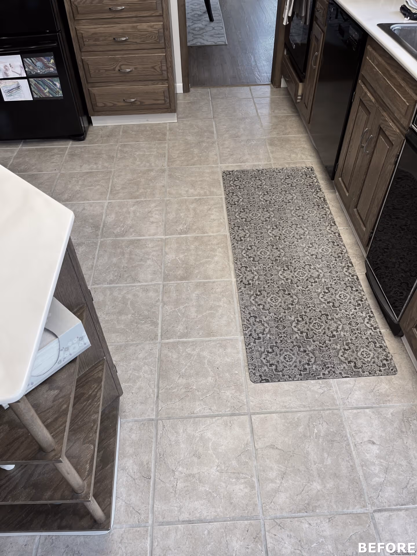 Modern kitchen in Harrisburg, PA featuring light ceramic tiles, wooden cabinetry, and a decorative gray rug.