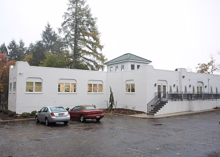White building exterior with modern design features, located in Camp Hill, PA, surrounded by trees and a parking area.
