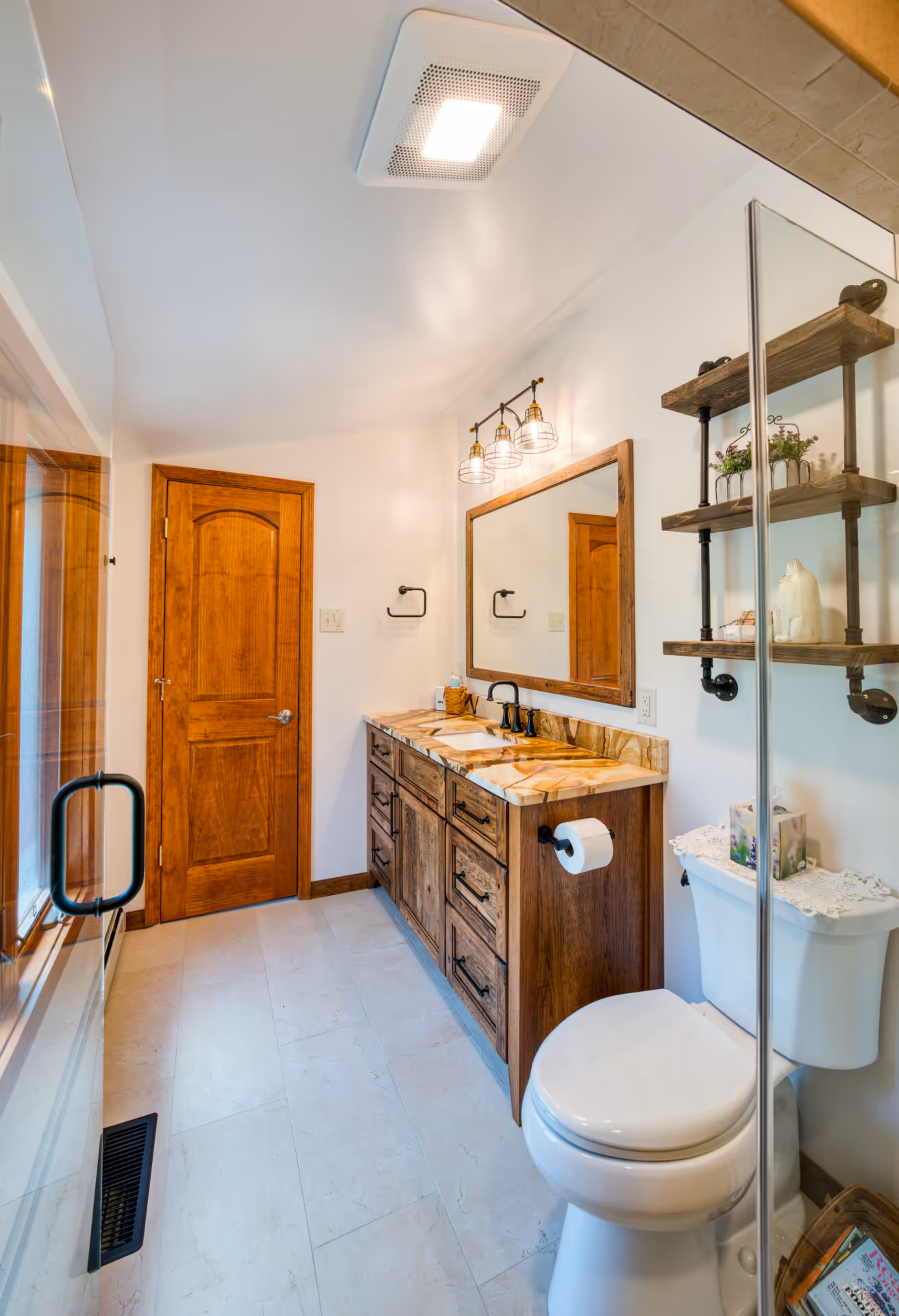 Transitional bathroom in Dillsburg, PA featuring wooden cabinetry, stone countertop, and stylish lighting