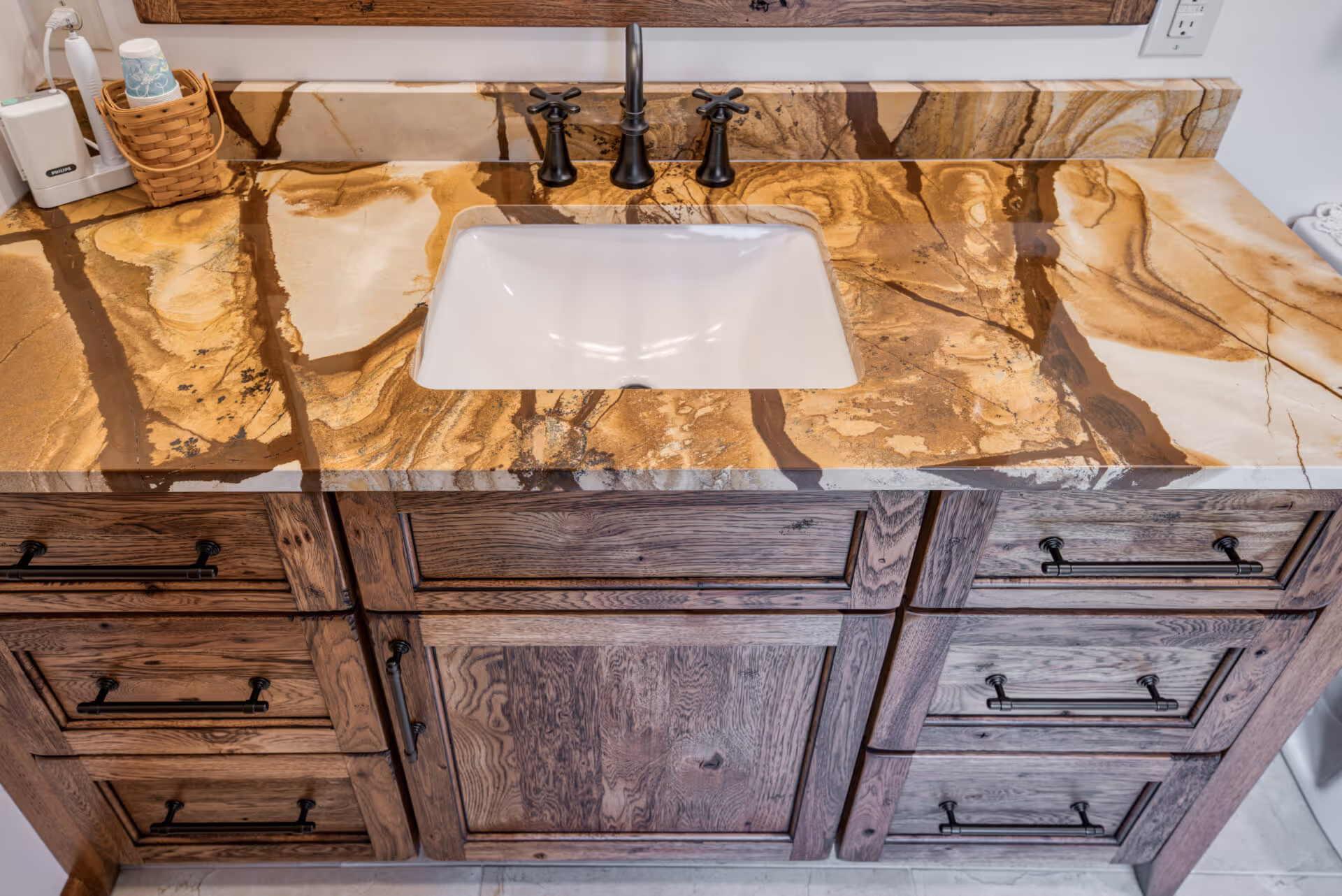 Luxury bathroom in Dillsburg, PA featuring an elegant wood vanity with a stunning stone countertop and black fixtures.