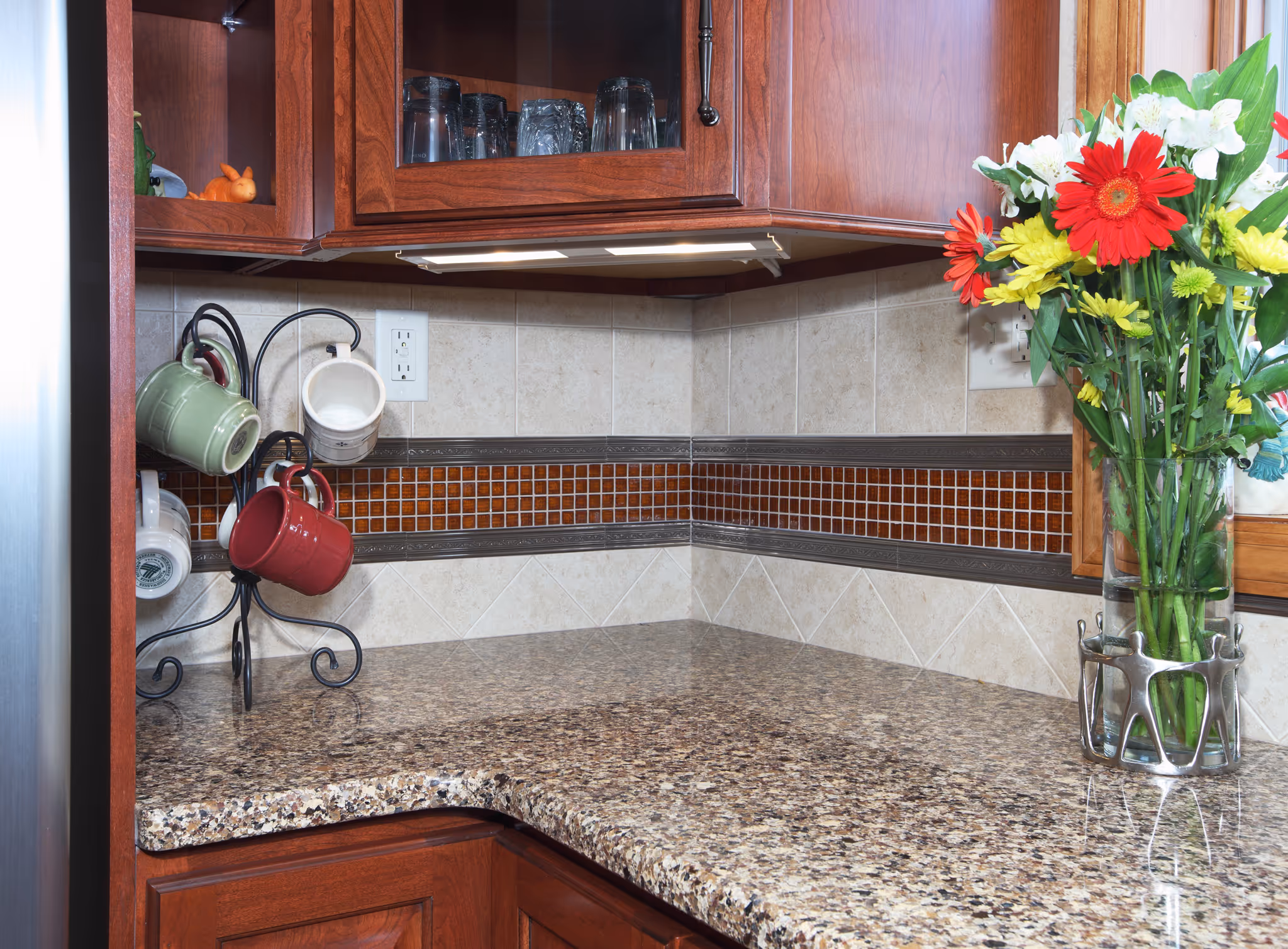 Modern kitchen with granite countertops, wooden cabinets, colorful mugs, and floral arrangement in York, PA