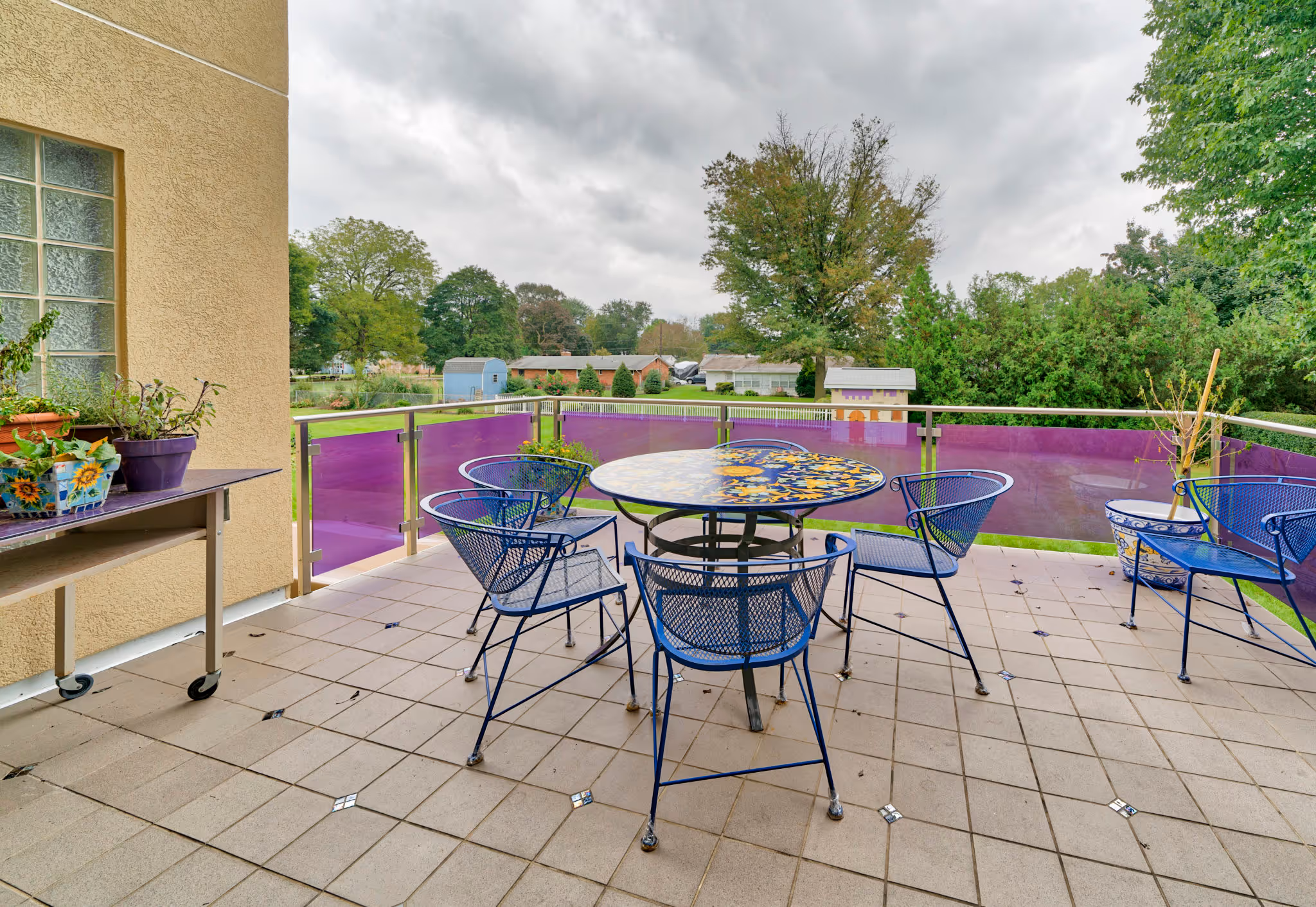 Outdoor patio space featuring vibrant painted table and blue wire chairs in Camp Hill, PA