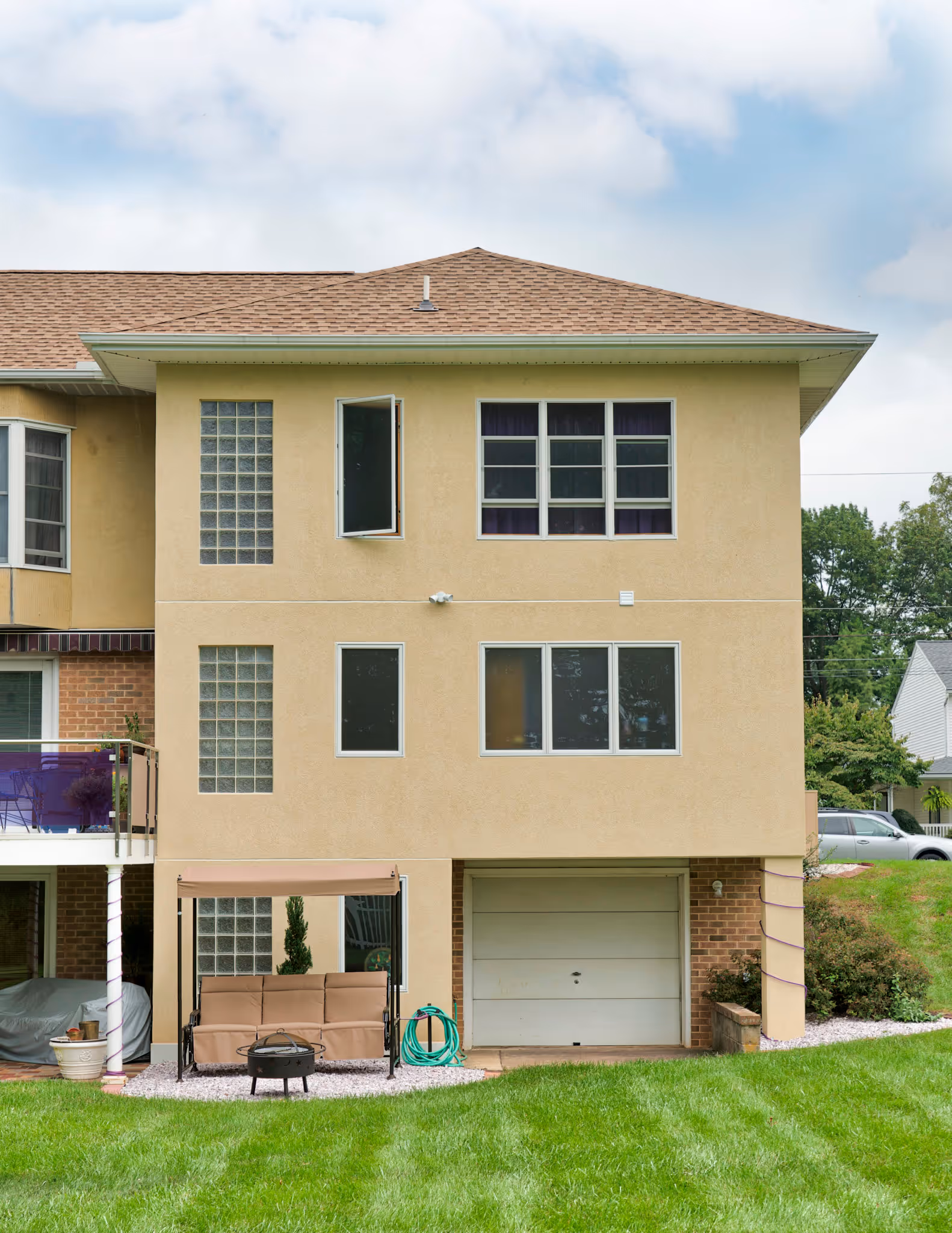 Exterior view of a tan house with a covered patio swing and green lawn in Camp Hill, PA.