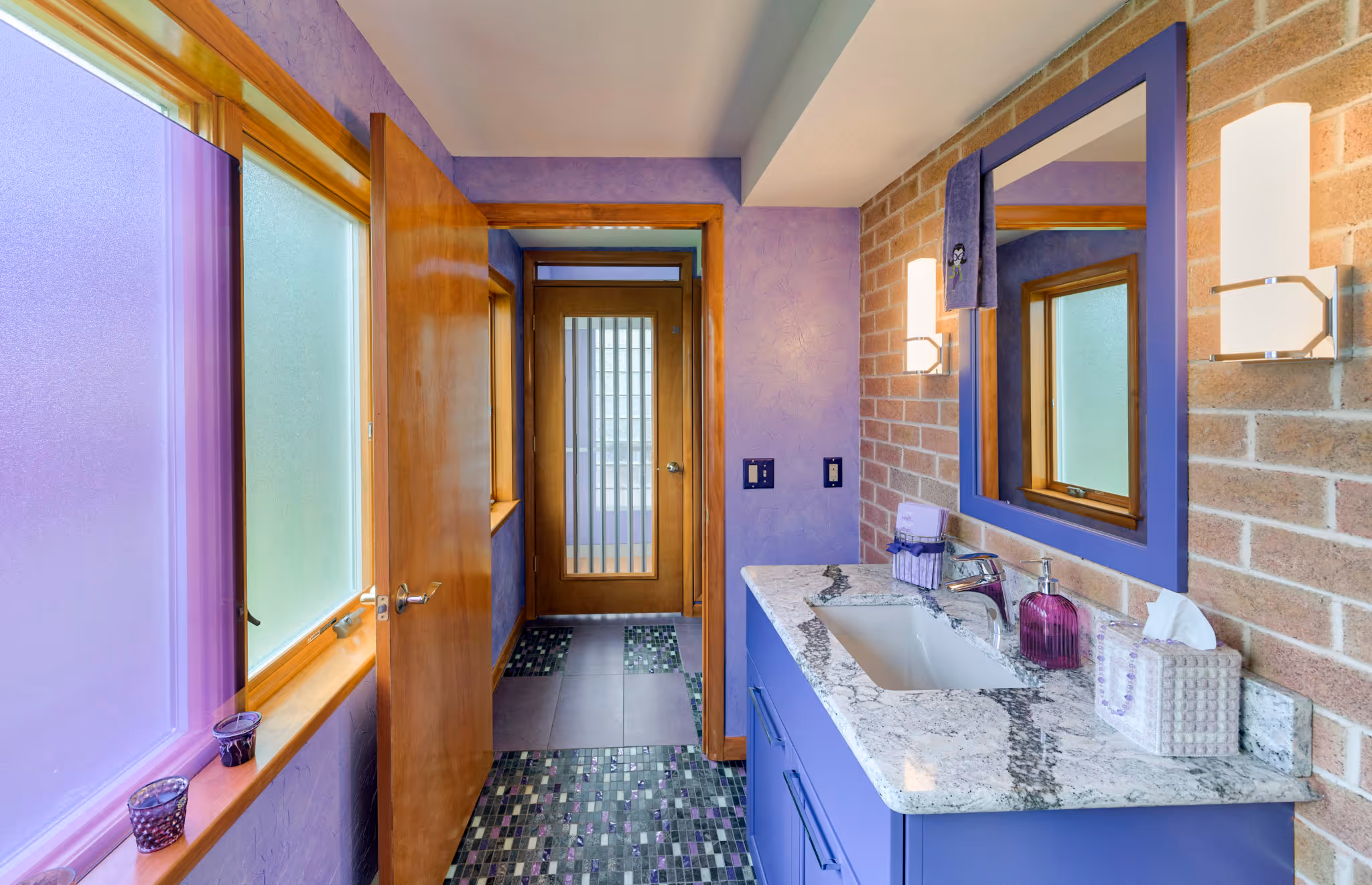 Modern bathroom with purple accents, granite countertop, and brick wall in Camp Hill, PA.