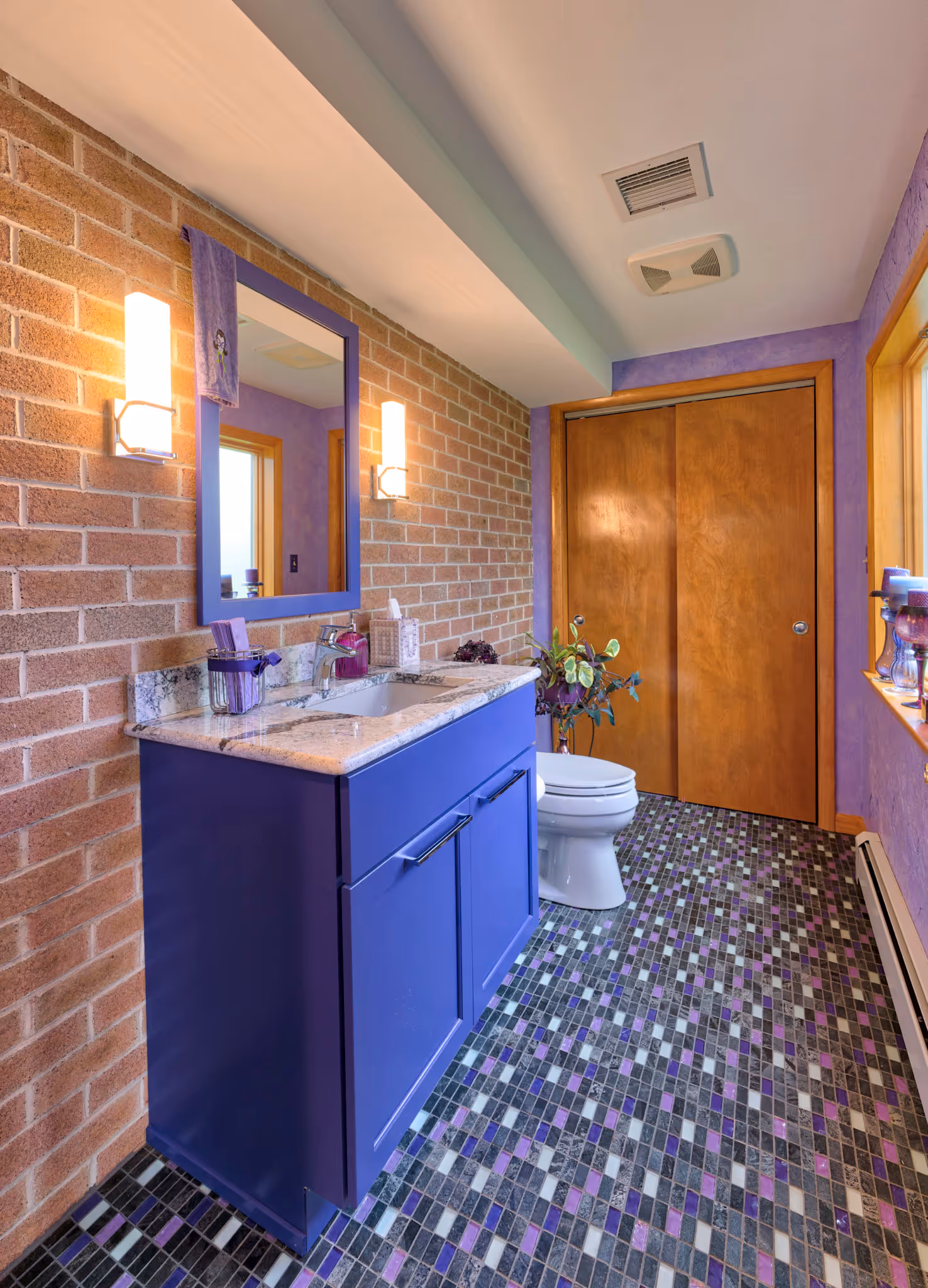 Vibrant purple bathroom featuring a modern sink, brick wall, and colorful tile flooring in Camp Hill, PA