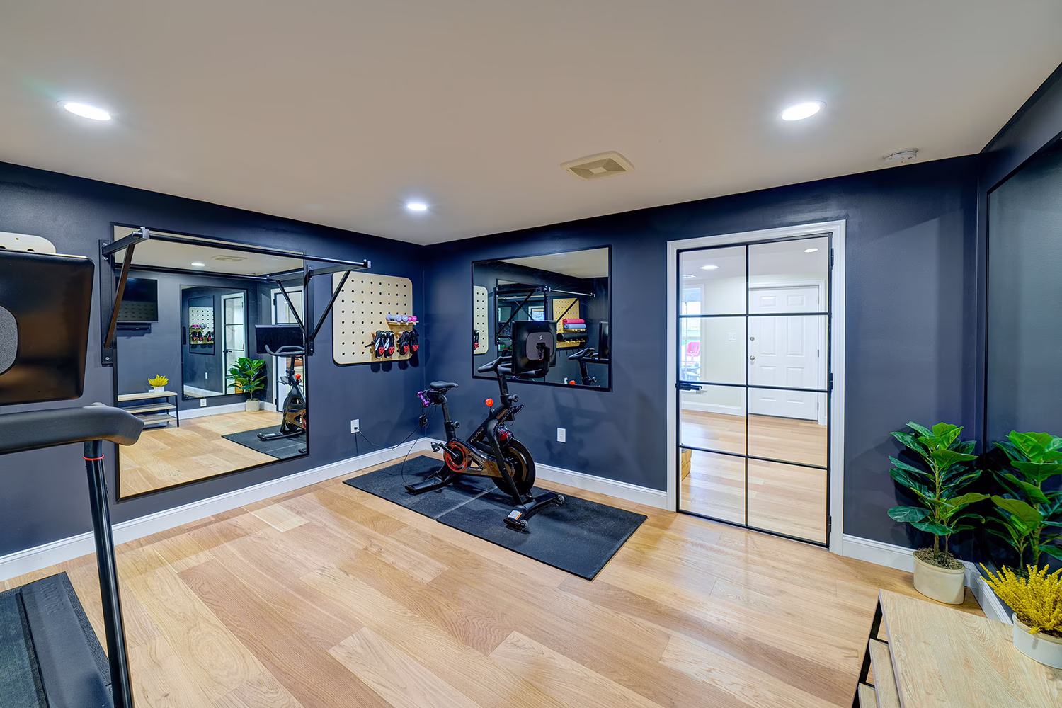 Modern home gym with workout equipment, mirrors, and dark walls in a Mechanicsburg, PA basement.