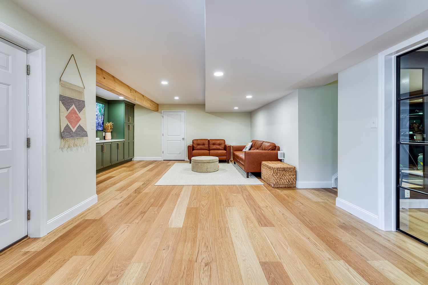 Stylish basement living area featuring leather sofas and warm wood flooring in Mechanicsburg, PA.