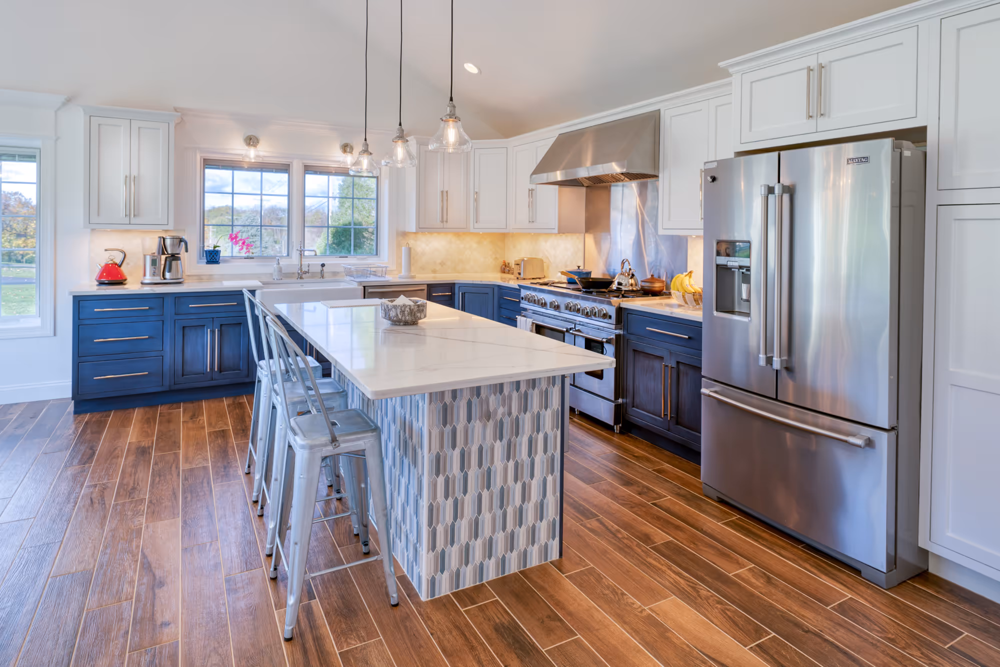 Contemporary kitchen in Etters, PA featuring a blue island, stainless steel appliances, and elegant lighting.