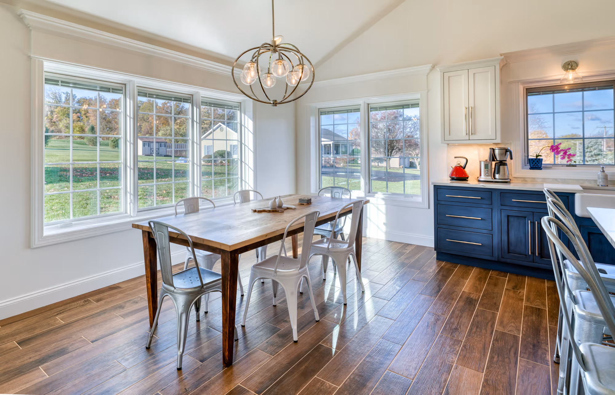 Modern dining area with a wooden table, metallic chairs, large windows, and dark cabinetry in etters, pa.