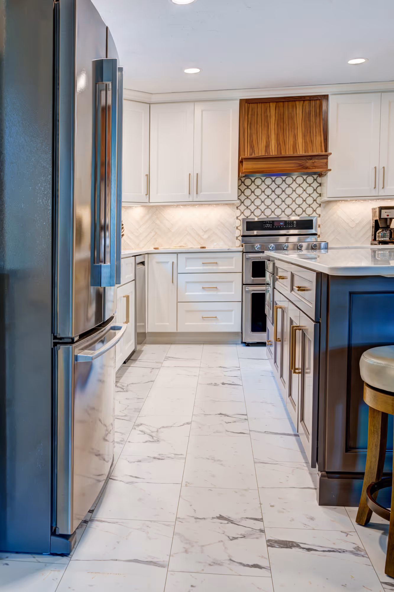 Modern kitchen remodel in Gettysburg, PA featuring white cabinets, marble floors, and contemporary pendant lights.