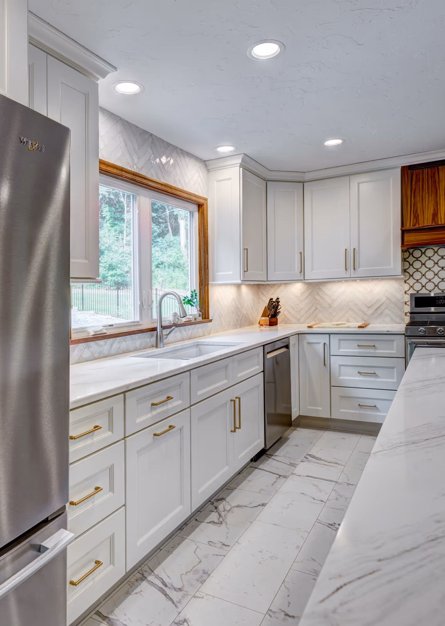 Modern kitchen in Gettysburg, PA featuring white cabinets, gold hardware, and herringbone backsplash.