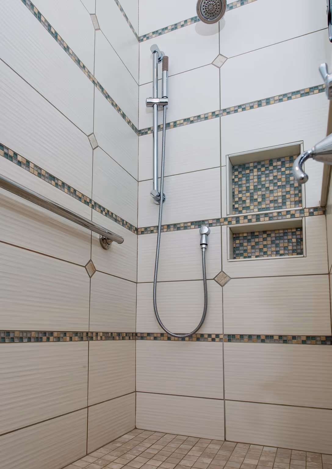Modern shower with white tiles, mosaic accents, and a handheld showerhead in Hummelstown, PA.