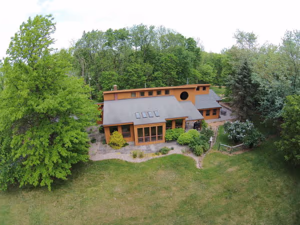 Modern passive solar house exterior in Mechanicsburg, PA, featuring large windows and surrounding lush greenery.