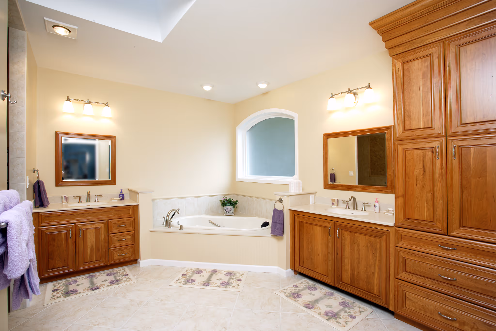 Spacious contemporary bathroom featuring a double vanity, soaking tub, and warm wooden cabinetry in Camp Hill, PA.