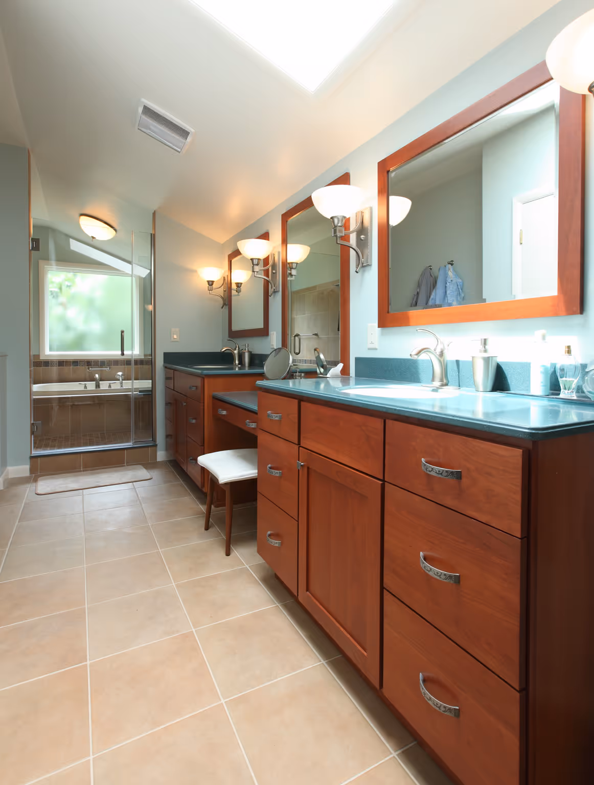 Modern bathroom in Carlisle, PA featuring light blue walls, dark countertops, and wooden cabinets.