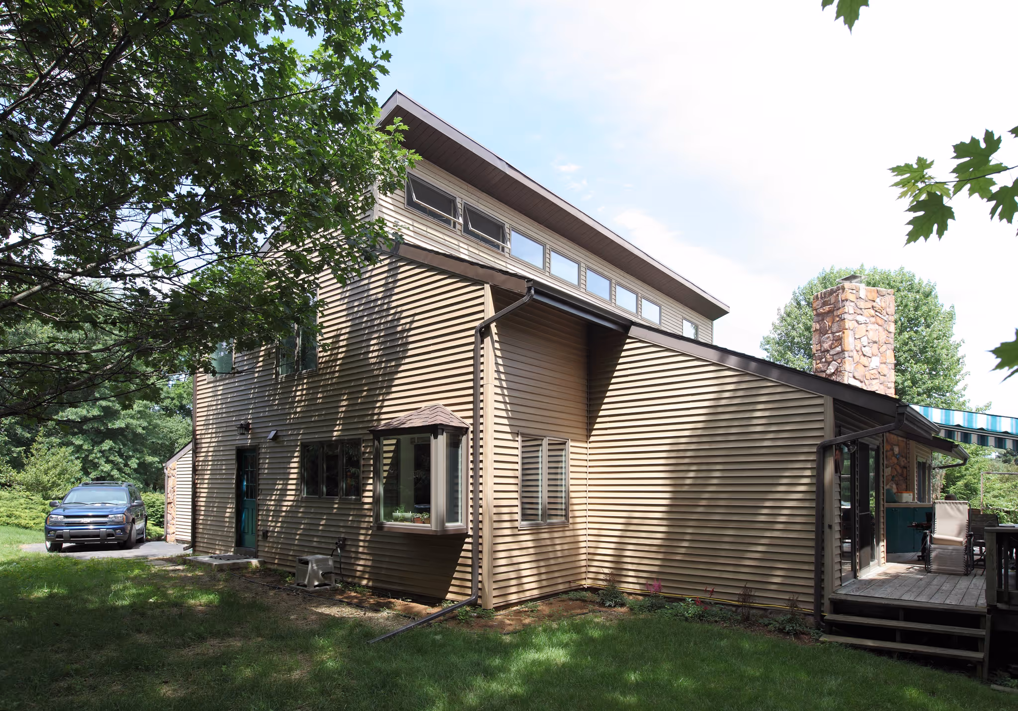 Modern exterior view of a contemporary home in Carlisle, PA with natural stone chimney and lush landscaping.