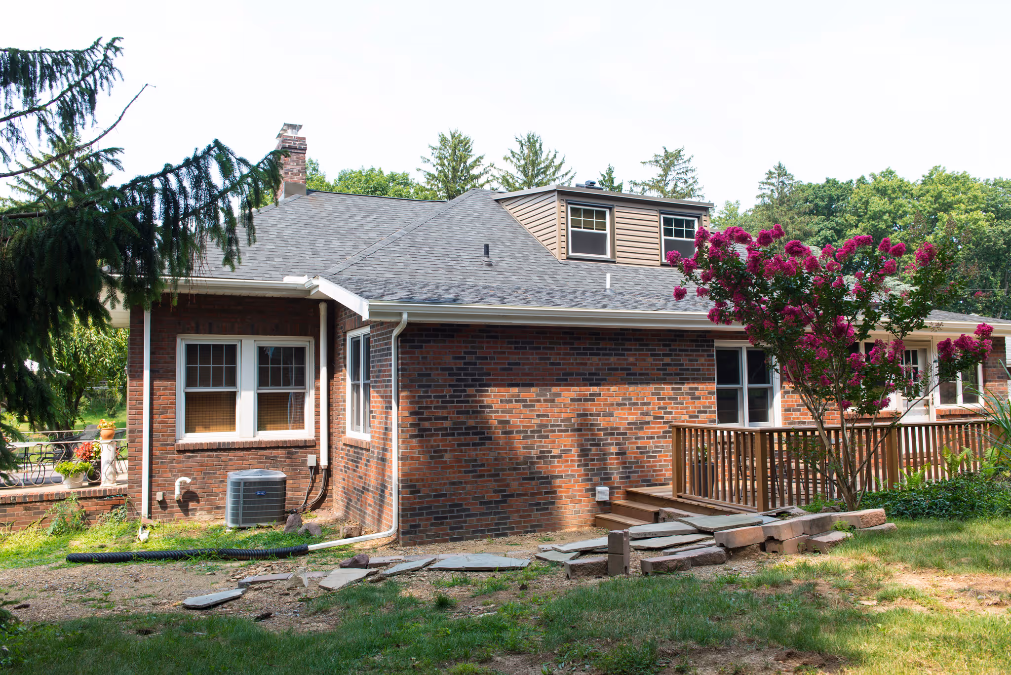 Charming brick exterior with a wooden deck and flowering tree in a residential area of harrisburg, pa