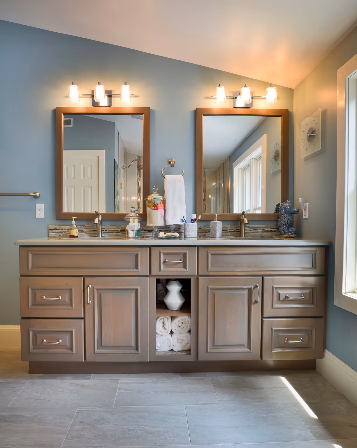 Spacious modern bathroom featuring double vanities, gray cabinetry, and elegant lighting in Harrisburg, PA.
