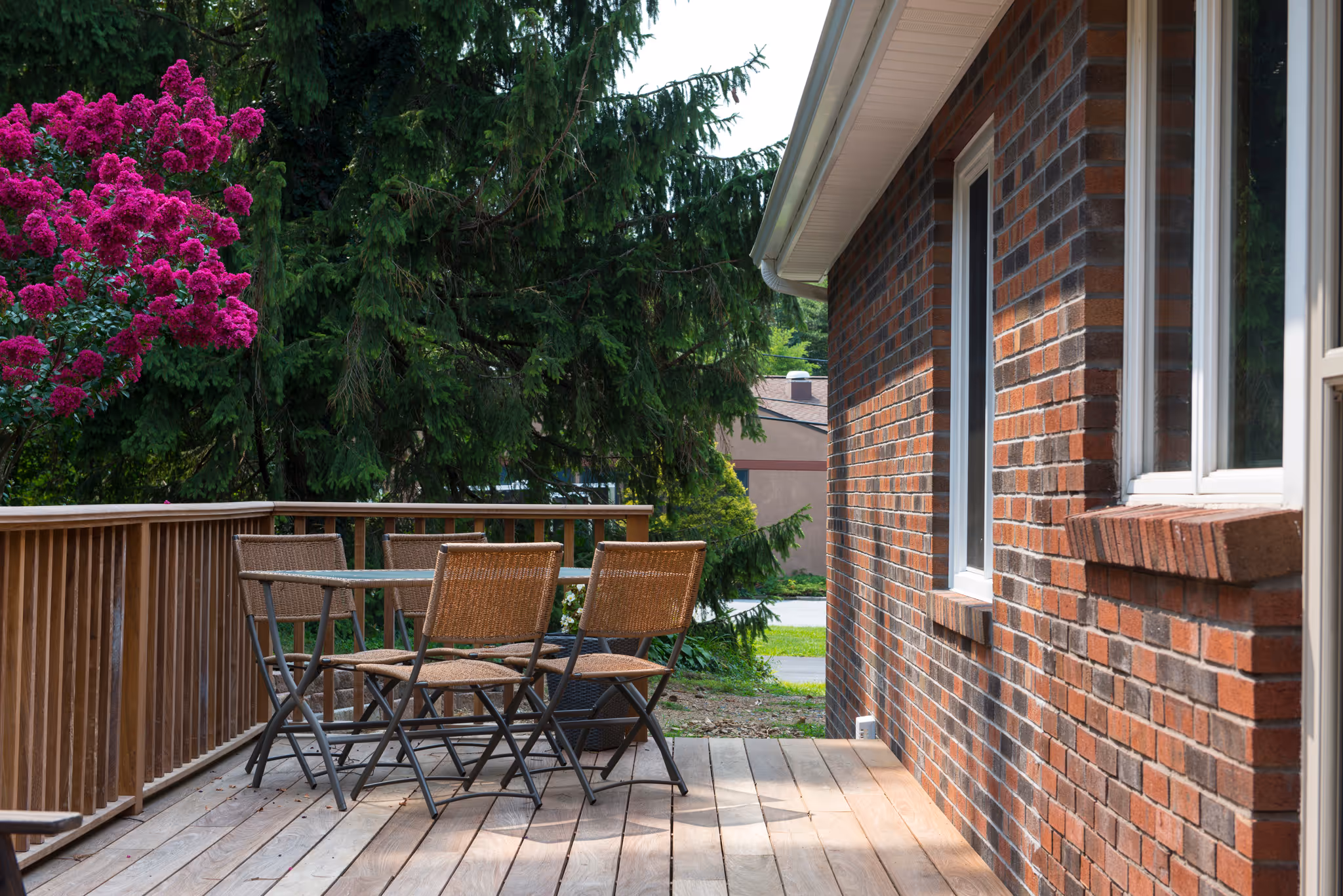 Cozy outdoor deck with wicker dining furniture and vibrant flowering trees in Harrisburg, PA.