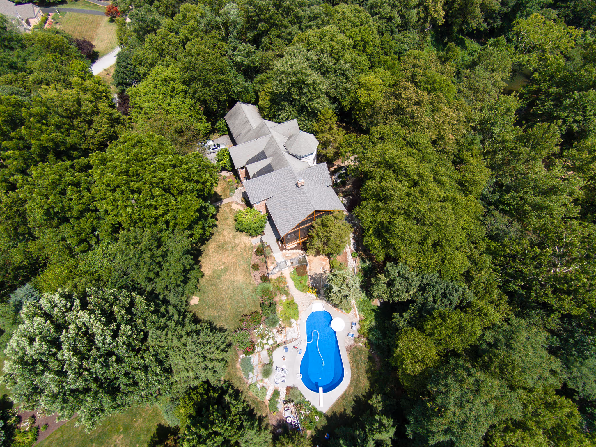 Aerial view of a green landscape featuring a large home with a swimming pool in Camp Hill, PA