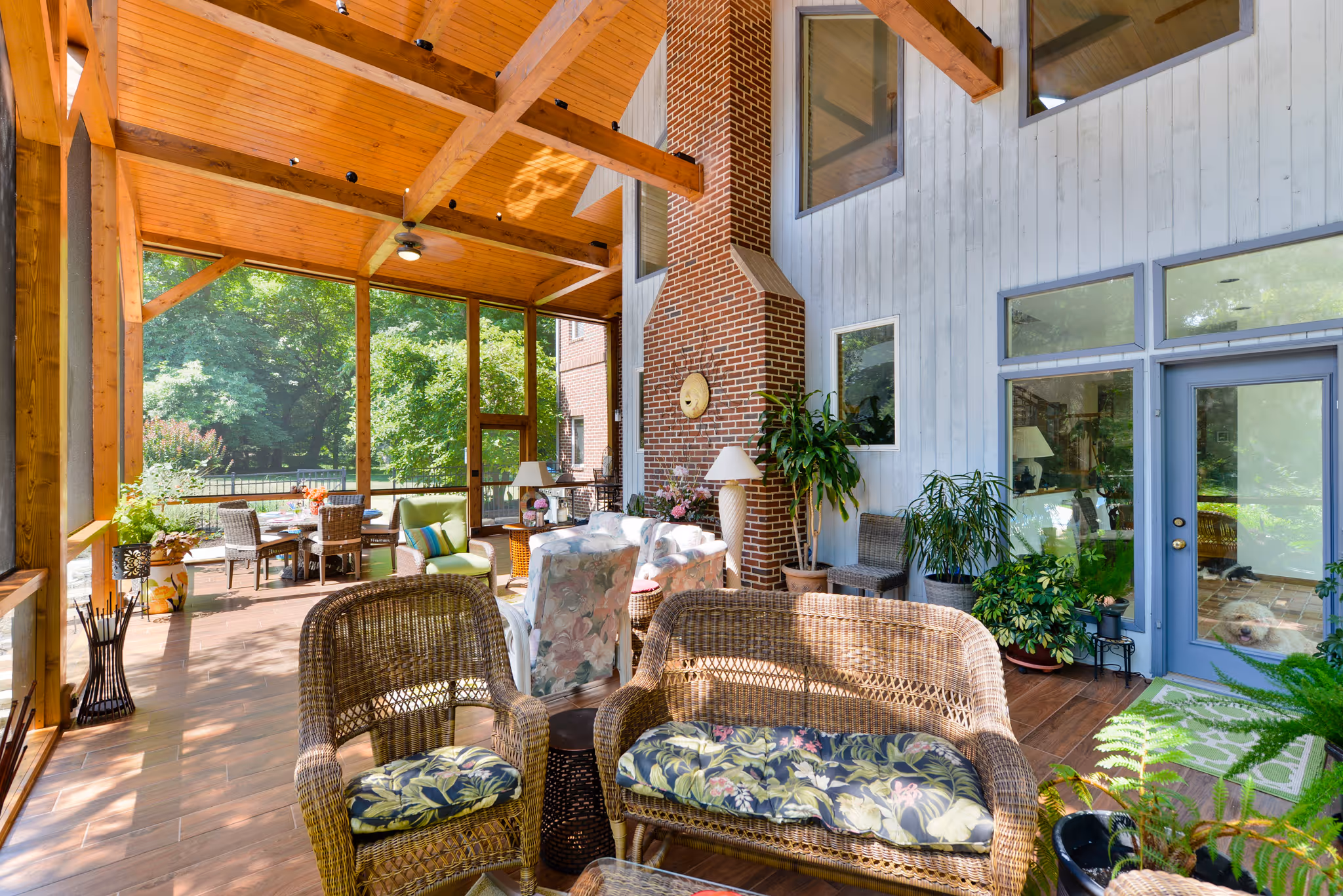 Bright sunroom with wooden beams, brick accent wall, and lush greenery in Camp Hill, PA.
