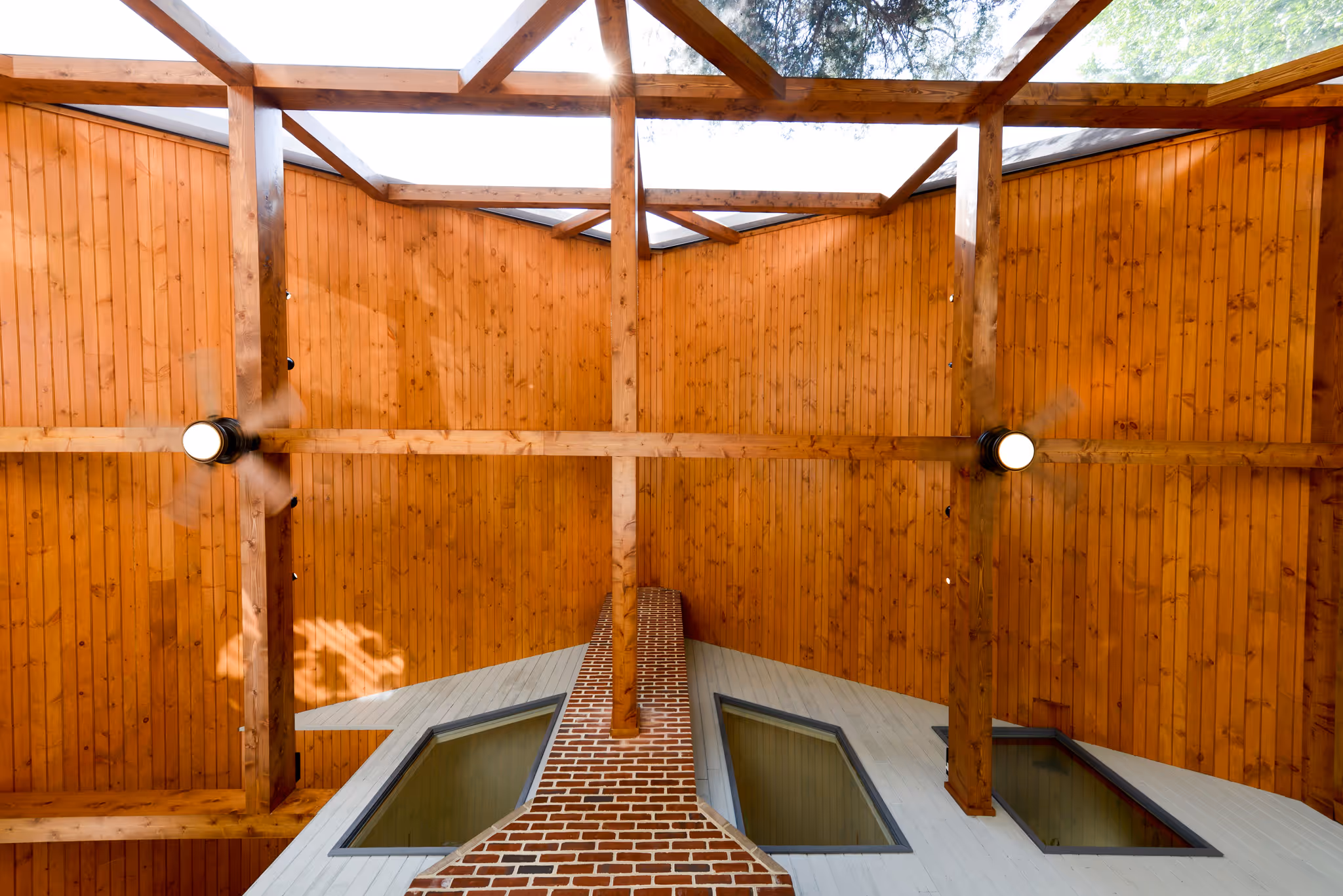 Modern interior of a room featuring a wooden ceiling, a brick chimney, and large skylights in Camp Hill, PA.