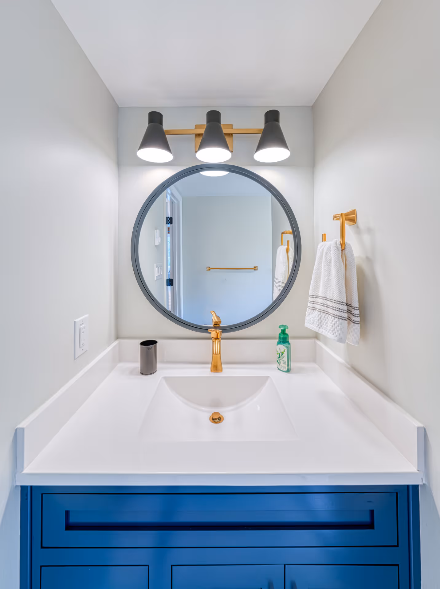 Modern bathroom with round mirror, gold faucet, and blue vanity in new cumberland, pa