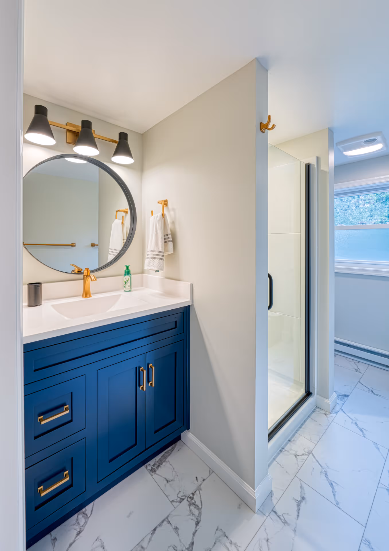 Elegant transitional bathroom in New Cumberland, PA featuring a blue vanity and modern fixtures.
