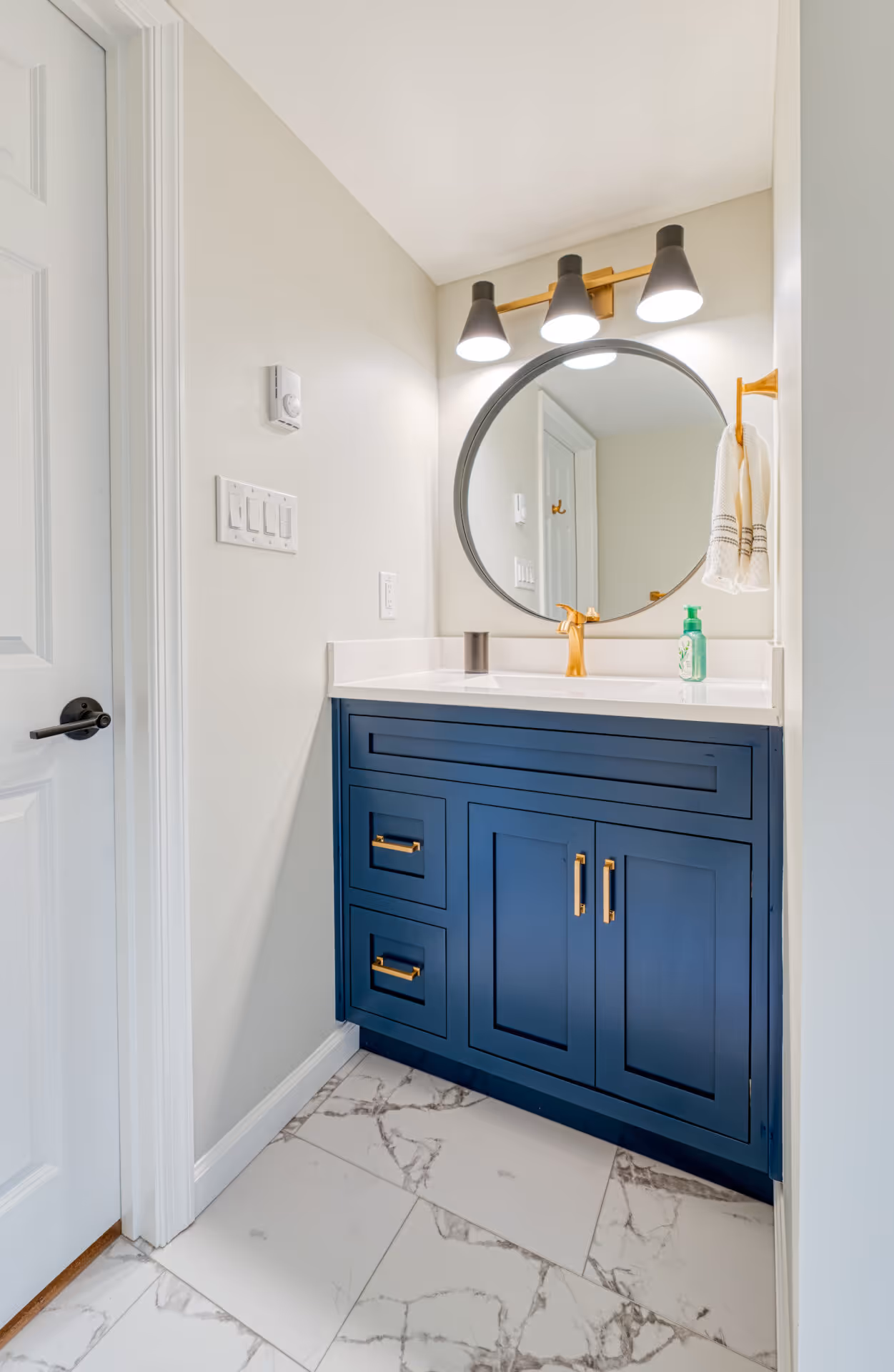 Modern bathroom in New Cumberland, PA featuring a navy blue vanity and elegant gold fixtures