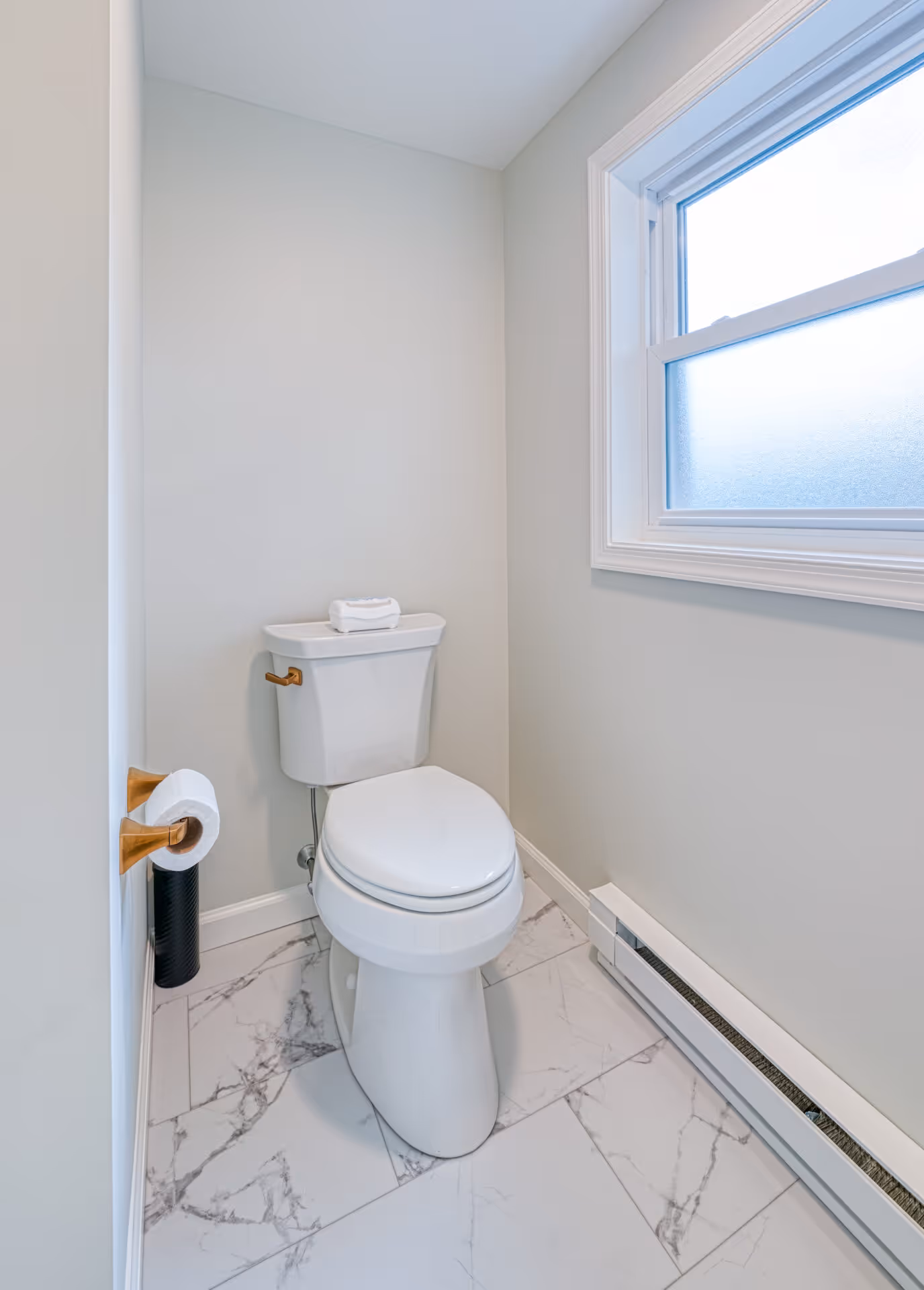 Modern bathroom featuring a white toilet and marble tile flooring in New Cumberland, PA.