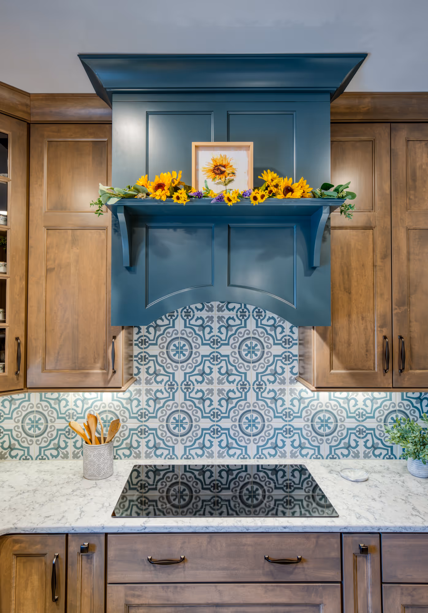 Stylish kitchen in Mechanicsburg, PA featuring a blue hood, decorative shelf, and patterned backsplash.
