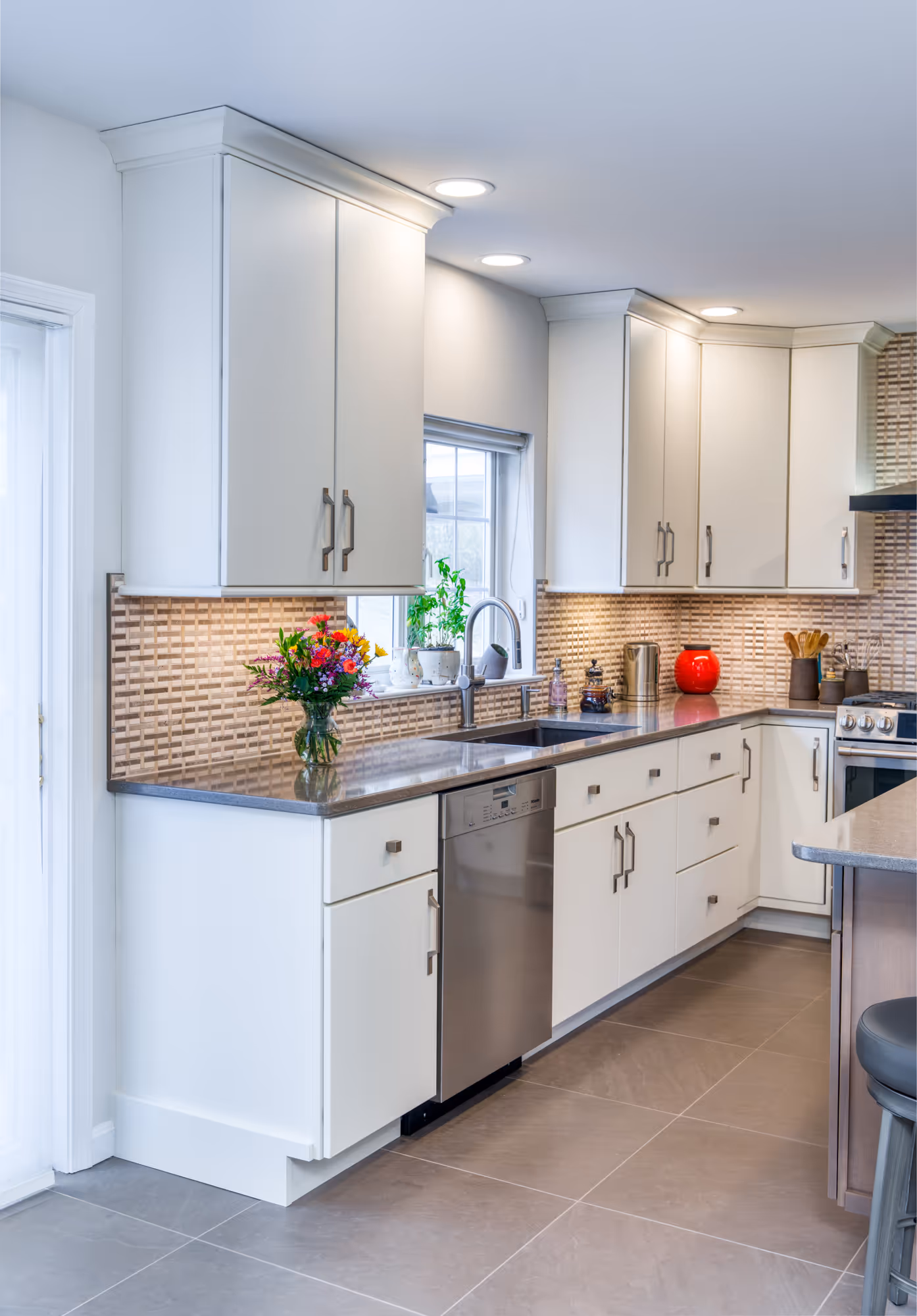 Modern kitchen in Hummelstown, PA featuring white cabinetry, a granite countertop, and stylish mosaic backsplash.