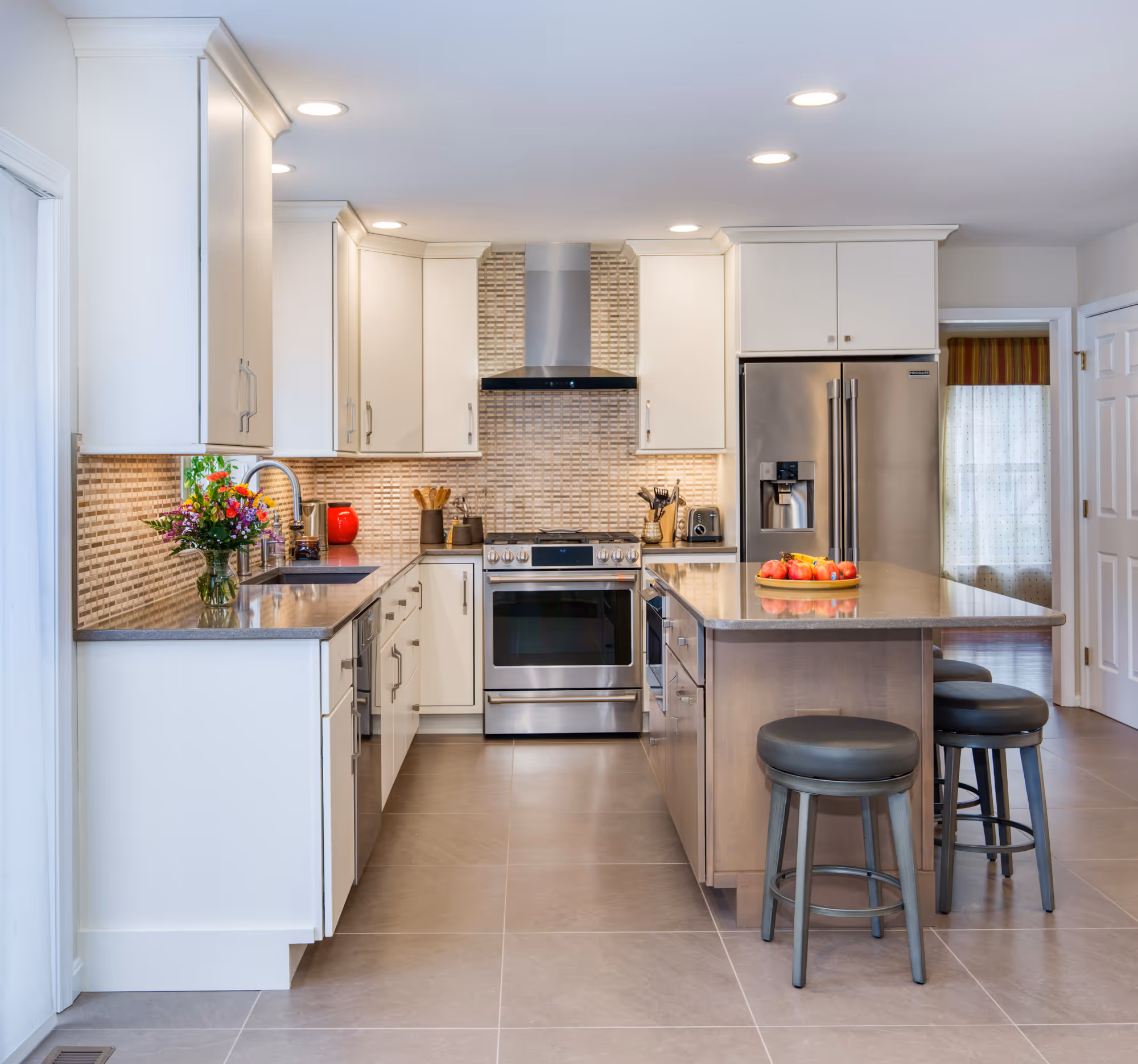 Modern kitchen in Hummelstown, PA with sleek white cabinetry, stainless steel appliances, and brown textured tile backsplash.