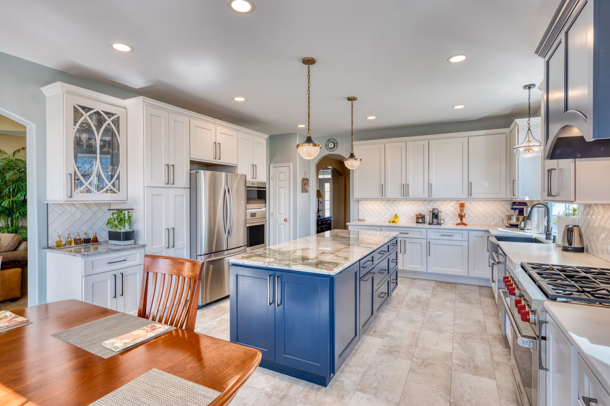 Modern kitchen in enola, pa featuring white cabinetry, a blue island, and stainless steel appliances, perfect for family gatherings.