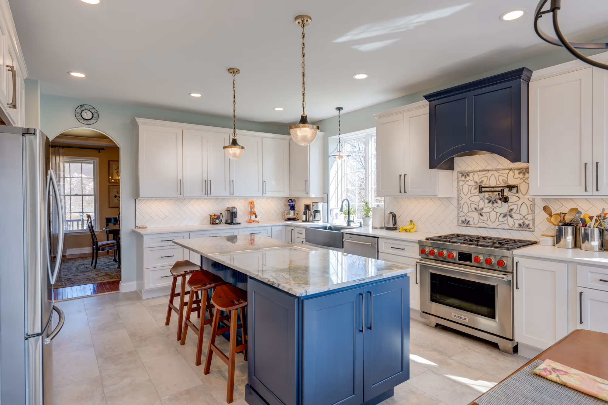Elegant kitchen in enola, pa featuring navy cabinets, a large island with marble countertop, and modern pendant lighting.