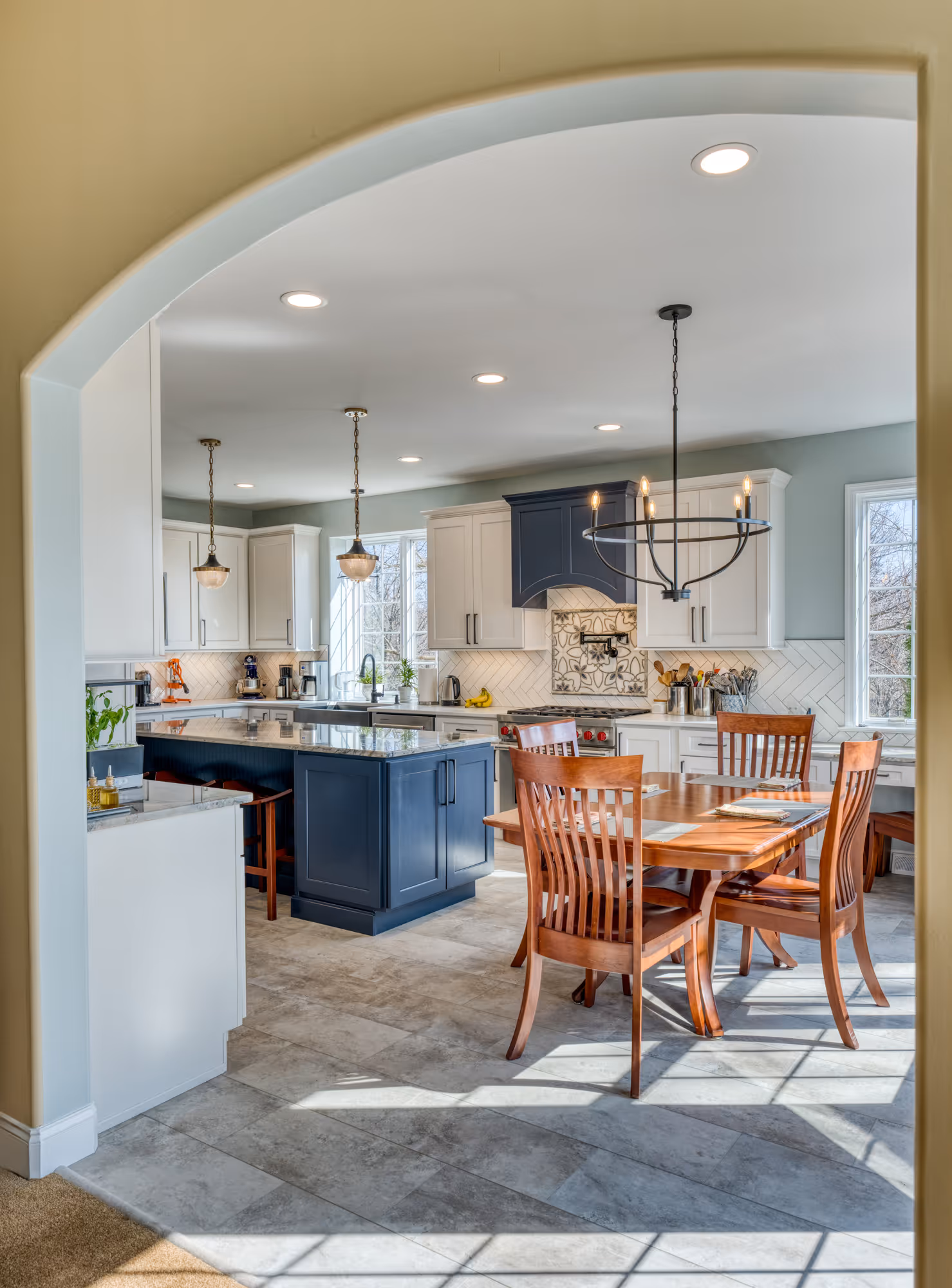 Contemporary kitchen with white and blue cabinetry, marble countertops, and wooden dining set in enola, pa