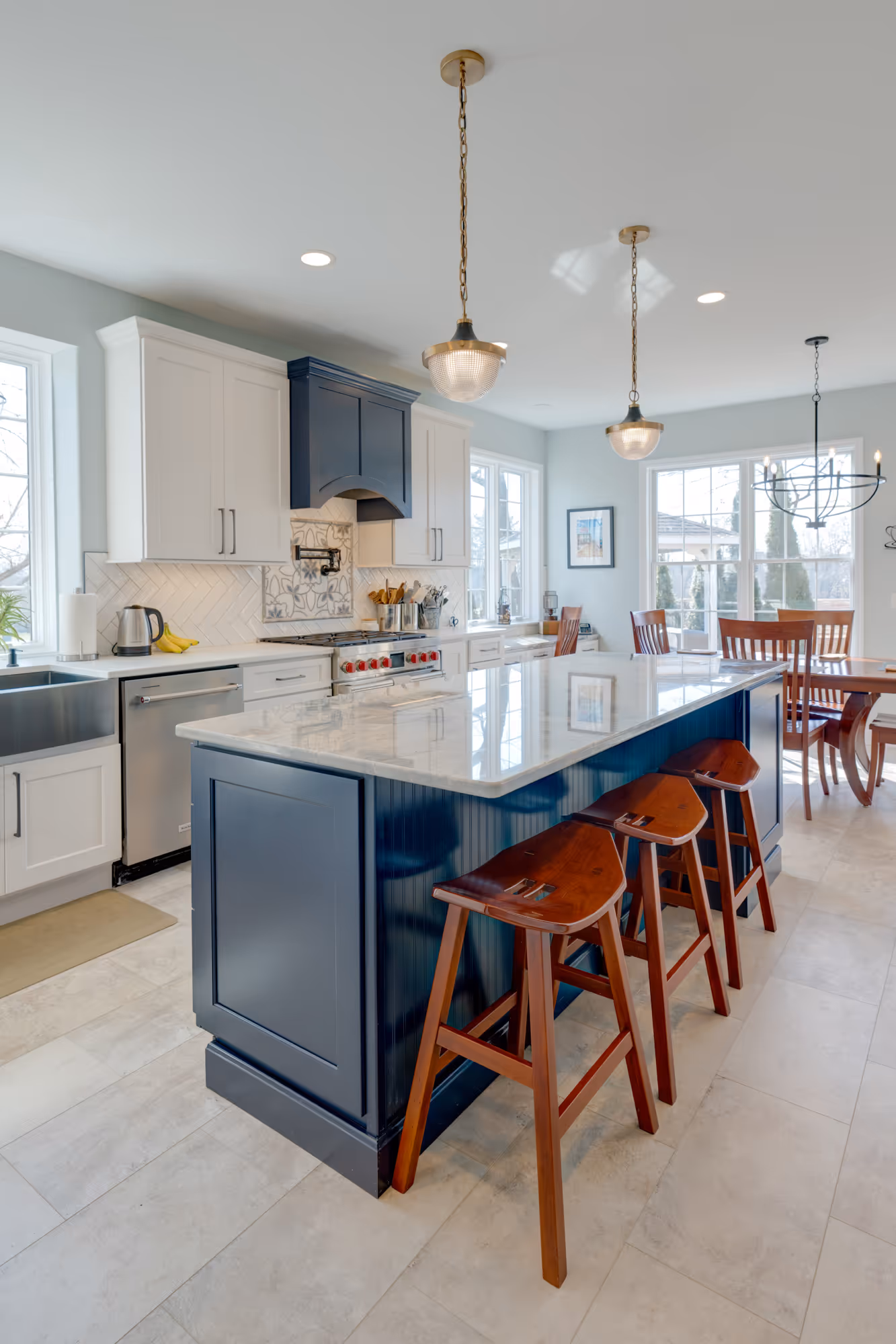 Modern kitchen in Enola, PA featuring a navy island, white cabinetry, and elegant pendant lights.