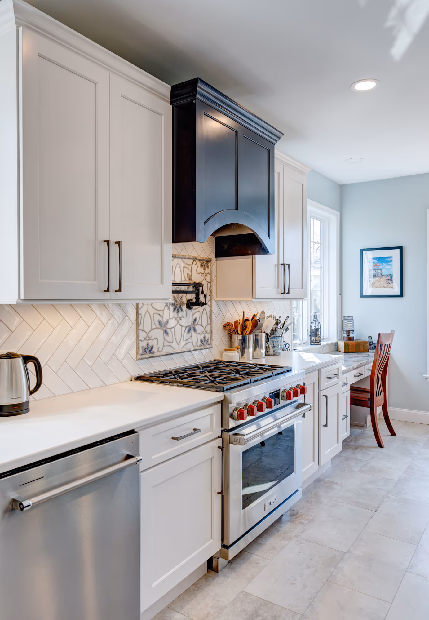 Modern kitchen in Enola, PA featuring a wolf range, herringbone backsplash, and white cabinetry.