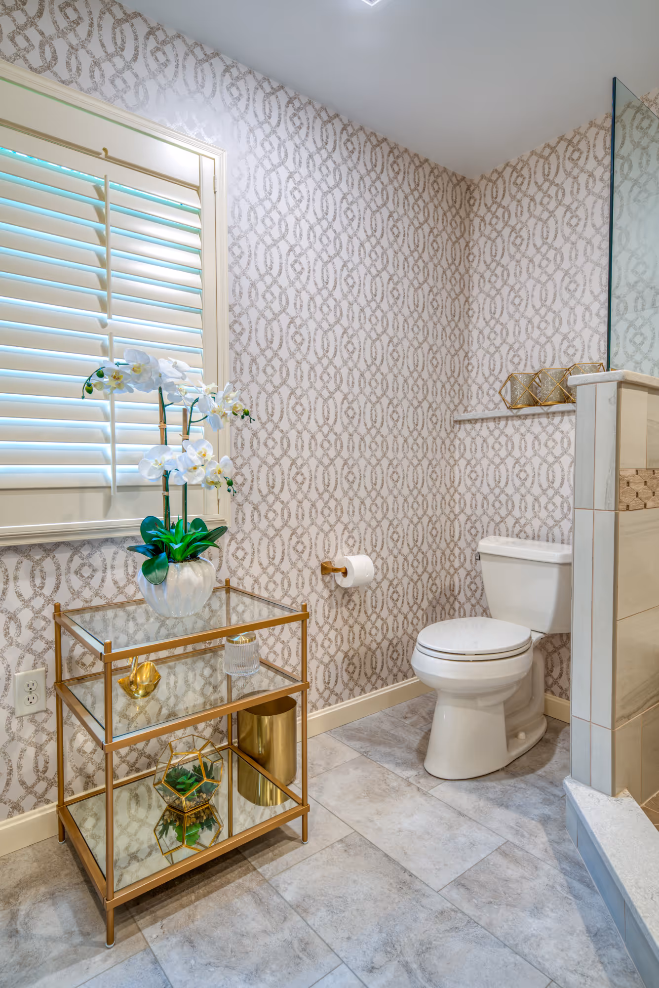 Elegant primary bathroom with modern wallpaper and a stylish glass side table featuring a plant in Mechanicsburg, PA.