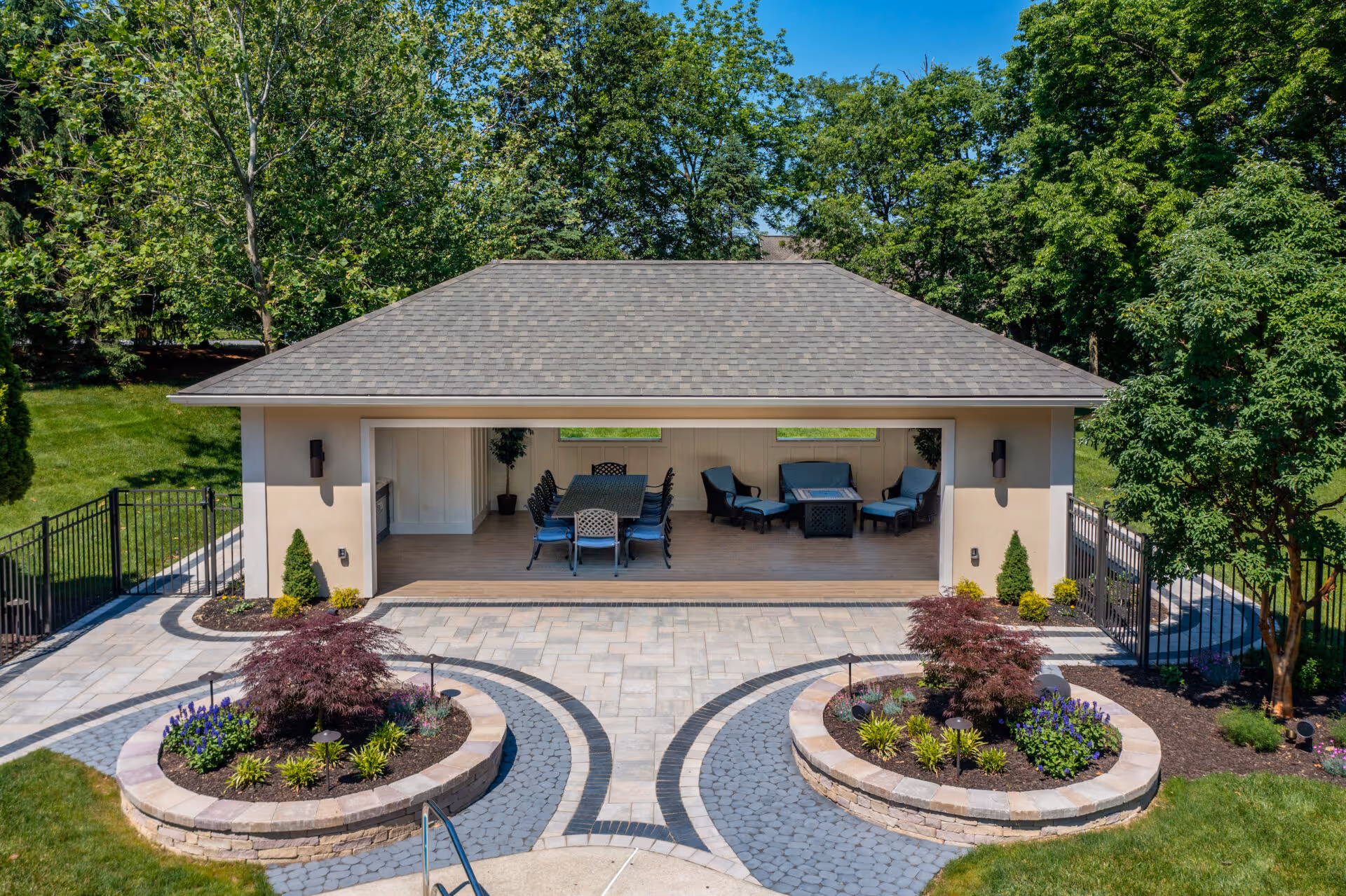 Stylish outdoor poolhouse with seating and dining area, located in Mechanicsburg, PA, surrounded by lush greenery.