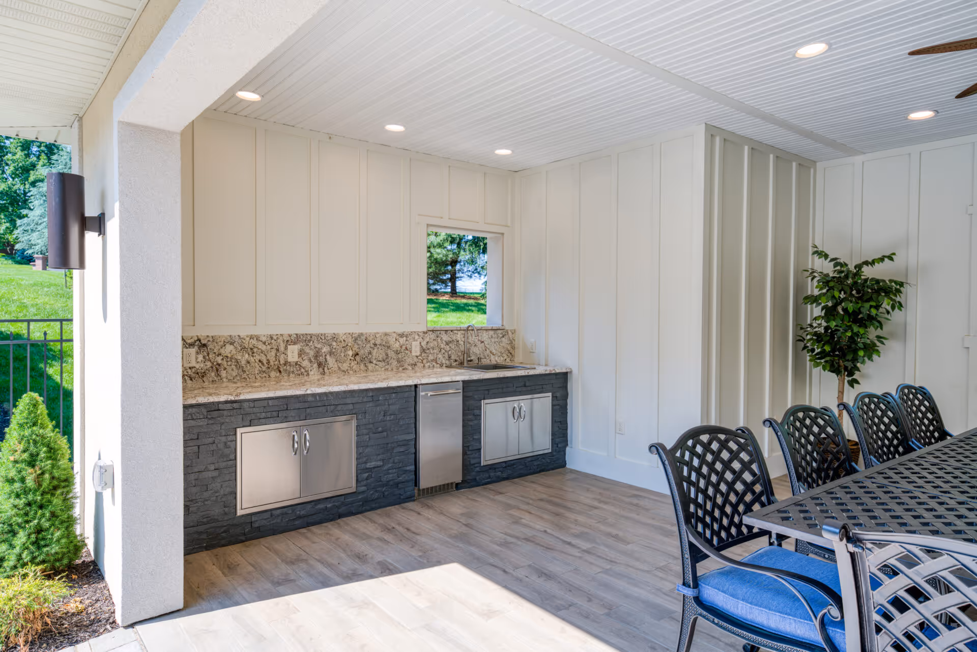 Contemporary outdoor kitchen with granite countertops, stainless steel appliances, and dining area in Mechanicsburg, PA.