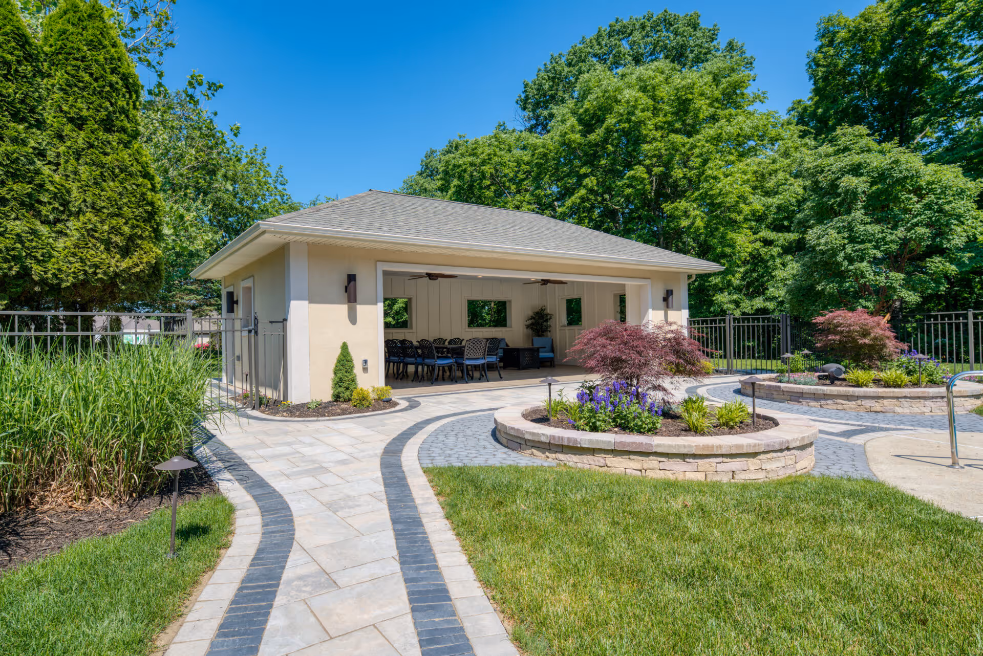 Luxurious pool house in Mechanicsburg, PA featuring a spacious patio and vibrant landscaping.